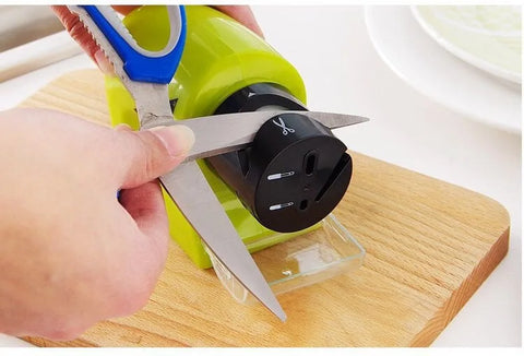 Knife sharpener being used on a pair of scissors with a wooden cutting board in the background.